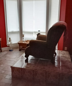A reclining chair placed on raised floor in a room with red walls.
