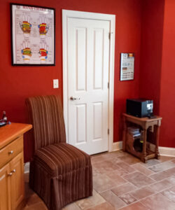 Interior of one of the massage rooms at Jenny's Reflexology and Massage including red walls, a framed hand reflexology poster and a striped chair.